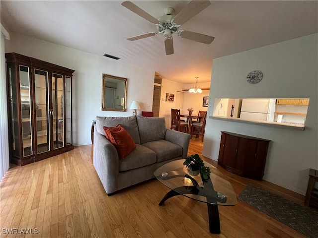 living room featuring ceiling fan with notable chandelier and light wood-type flooring