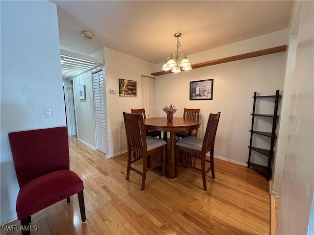 dining space with light hardwood / wood-style flooring and a notable chandelier