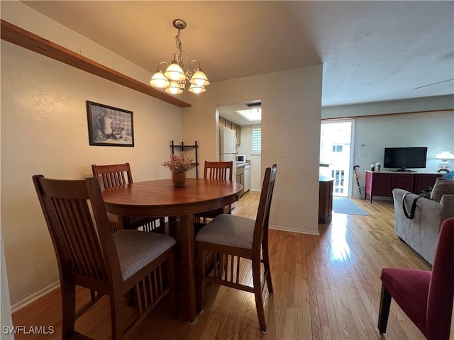 dining area with light wood-type flooring and an inviting chandelier