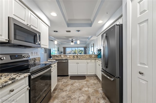 kitchen featuring kitchen peninsula, stainless steel appliances, a raised ceiling, decorative light fixtures, and white cabinetry