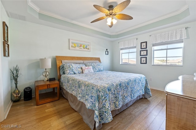 bedroom featuring hardwood / wood-style floors, ceiling fan, and a tray ceiling