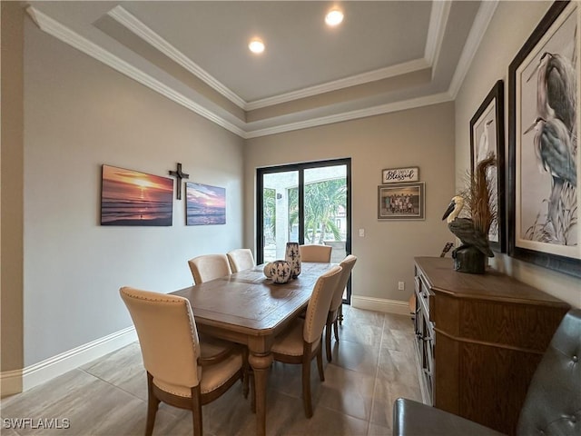 tiled dining room featuring ornamental molding and a raised ceiling