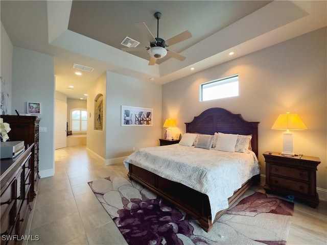 tiled bedroom featuring multiple windows, a tray ceiling, and ceiling fan