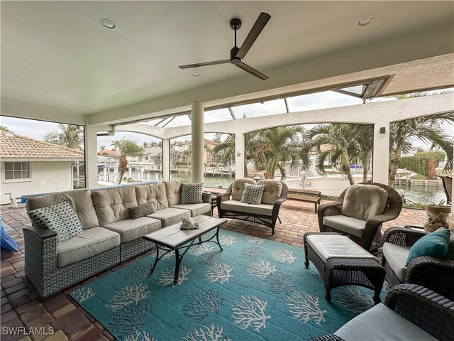 sunroom featuring a water view, ceiling fan, and plenty of natural light