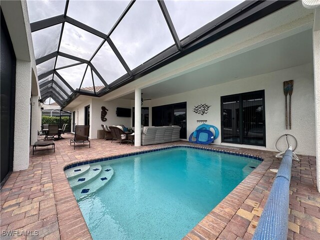 view of pool featuring a patio area, ceiling fan, glass enclosure, and an outdoor hangout area