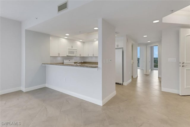 kitchen featuring white cabinetry, stone countertops, kitchen peninsula, fridge, and stove