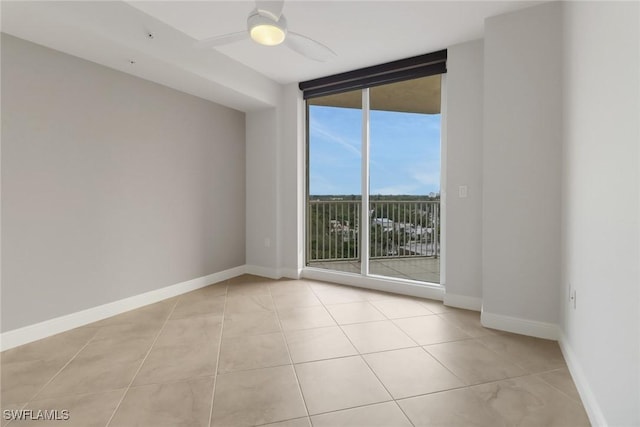 tiled spare room featuring ceiling fan and floor to ceiling windows