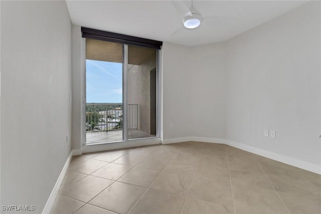 unfurnished room with ceiling fan, a wall of windows, and light tile patterned flooring