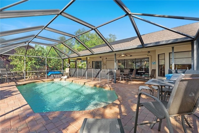 view of swimming pool featuring glass enclosure, ceiling fan, and a patio area