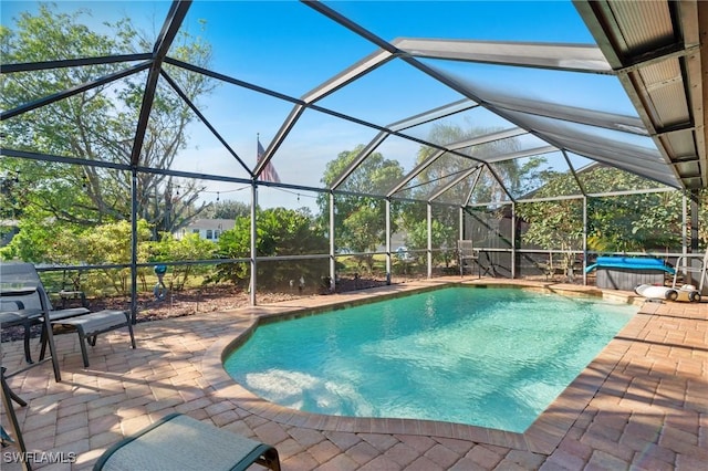 view of swimming pool featuring a jacuzzi, a patio, and a lanai