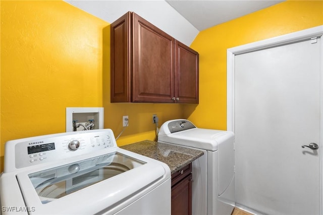 clothes washing area featuring cabinets and separate washer and dryer