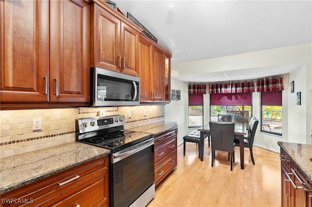 kitchen featuring light stone countertops, light wood-type flooring, stainless steel appliances, and tasteful backsplash