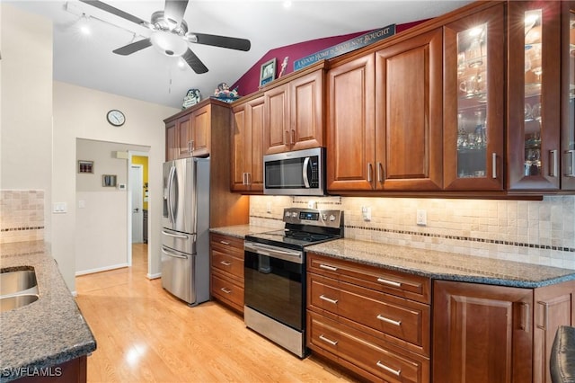 kitchen with lofted ceiling, stainless steel appliances, stone countertops, and light wood-type flooring