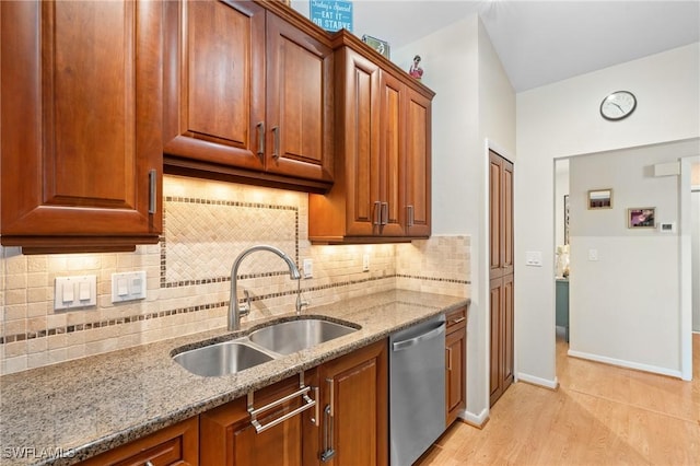 kitchen with decorative backsplash, light wood-type flooring, light stone counters, stainless steel dishwasher, and sink