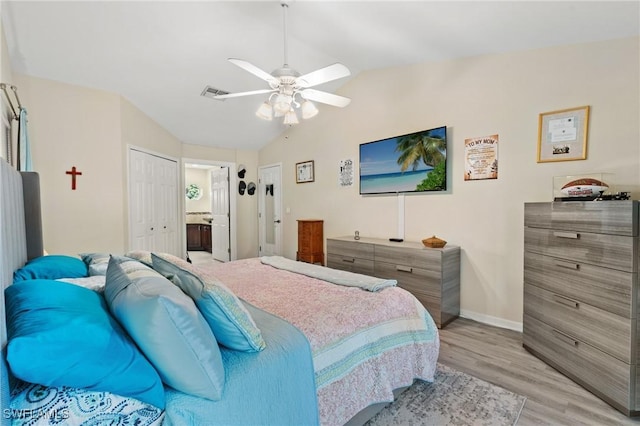 bedroom with ensuite bathroom, vaulted ceiling, light hardwood / wood-style flooring, ceiling fan, and a closet