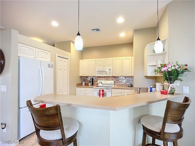 kitchen with a peninsula, white appliances, a breakfast bar, and light countertops