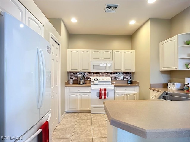 kitchen with white appliances, visible vents, a sink, and white cabinets