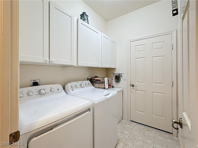 laundry room with light tile patterned floors, washer and clothes dryer, and cabinet space