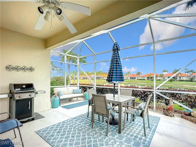 view of patio with area for grilling, glass enclosure, ceiling fan, a residential view, and an outdoor living space