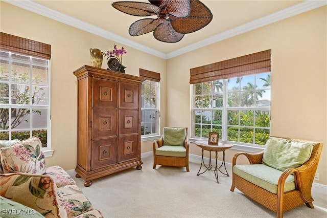 living area with ceiling fan, light colored carpet, and crown molding