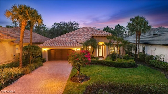 mediterranean / spanish home with a lawn and a garage