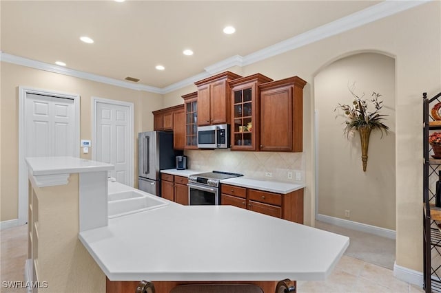 kitchen with a center island, a kitchen bar, stainless steel appliances, decorative backsplash, and crown molding