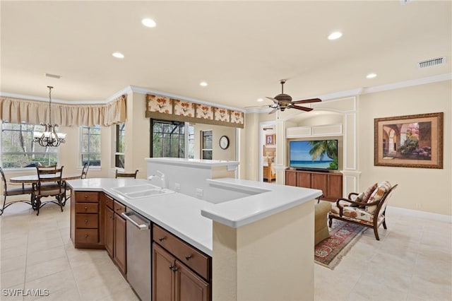 kitchen with ornamental molding, stainless steel dishwasher, ceiling fan with notable chandelier, and a center island with sink