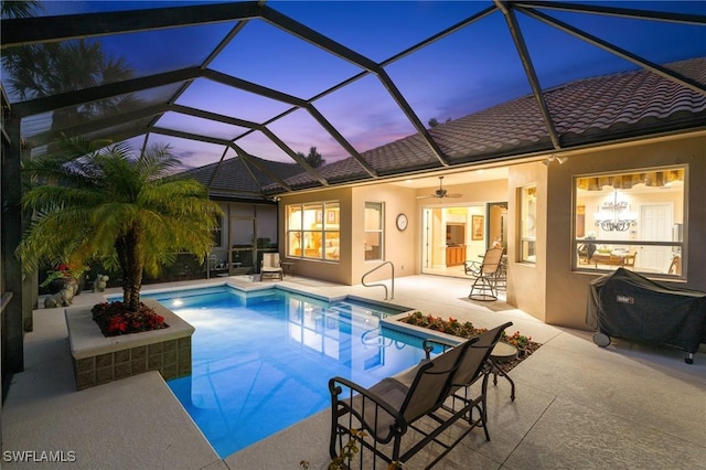 pool at dusk with ceiling fan, a lanai, and a patio area