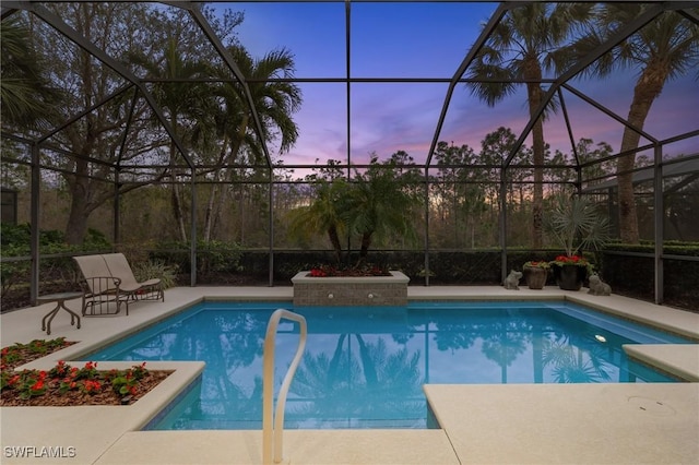 pool at dusk with a lanai and a patio area