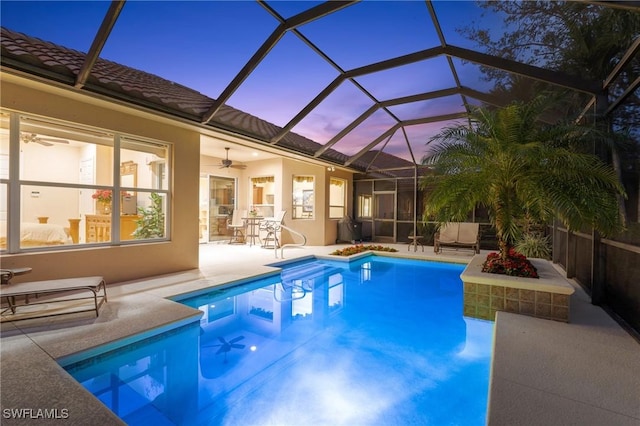 pool at dusk featuring ceiling fan, a patio area, and a lanai