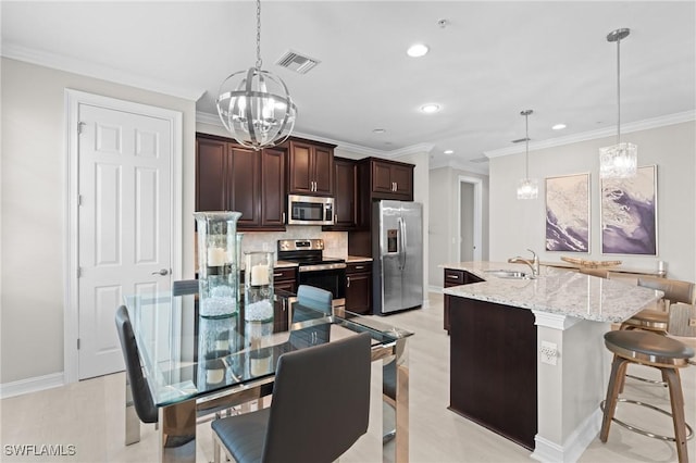 kitchen featuring pendant lighting, a center island with sink, decorative backsplash, sink, and stainless steel appliances