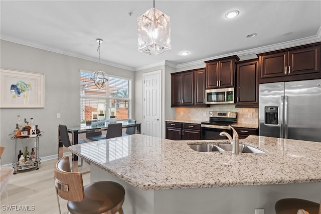 kitchen with an inviting chandelier, appliances with stainless steel finishes, hanging light fixtures, dark brown cabinetry, and sink