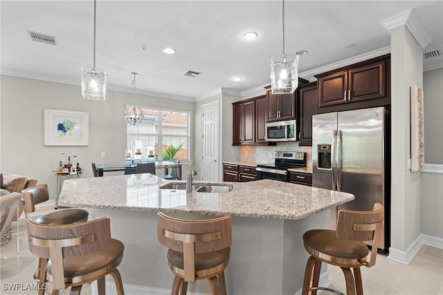 kitchen with tasteful backsplash, pendant lighting, sink, appliances with stainless steel finishes, and a breakfast bar area