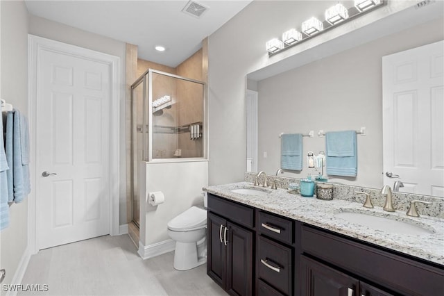 bathroom with toilet, a shower with door, and vanity