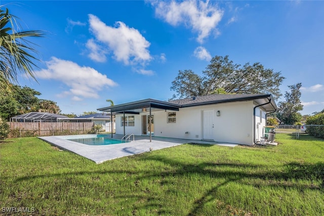 back of property with a fenced in pool, a patio area, and a lawn