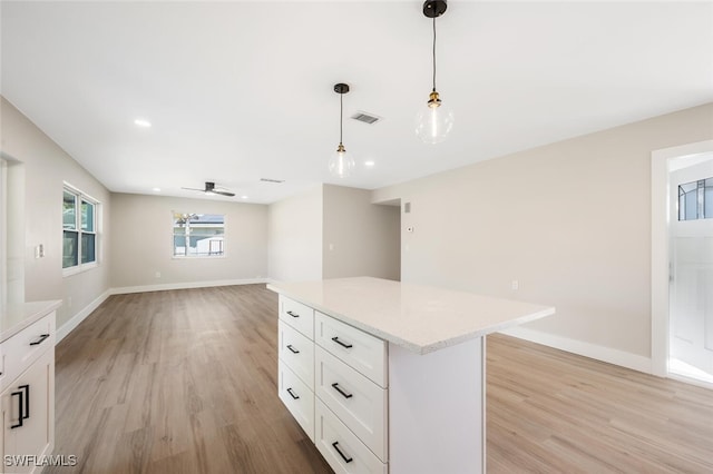 kitchen with a kitchen island, pendant lighting, white cabinetry, ceiling fan, and light hardwood / wood-style flooring