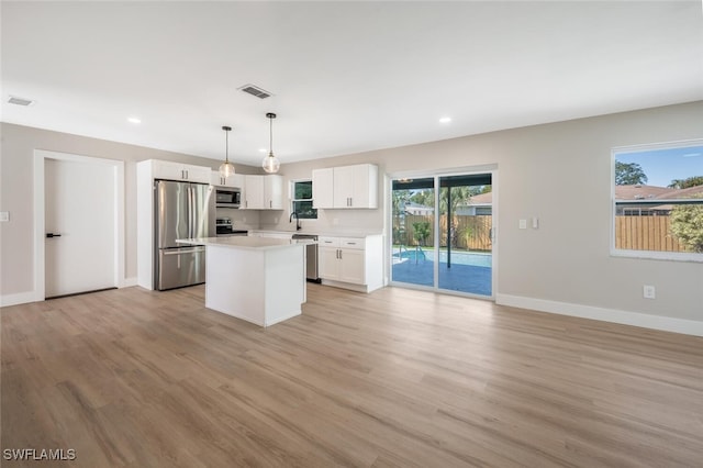 kitchen featuring pendant lighting, white cabinets, a center island, light hardwood / wood-style floors, and stainless steel appliances