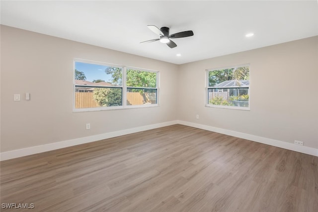 empty room with a healthy amount of sunlight, ceiling fan, and light hardwood / wood-style flooring