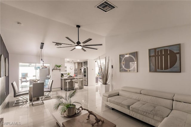 living room with light tile patterned floors, ceiling fan, and vaulted ceiling