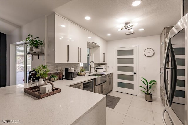 kitchen with backsplash, stainless steel refrigerator, white cabinets, light tile patterned flooring, and sink