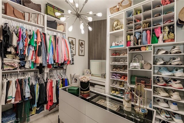 walk in closet featuring light tile patterned flooring and a chandelier