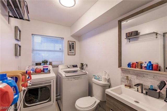 bathroom with toilet, decorative backsplash, washing machine and clothes dryer, and vanity