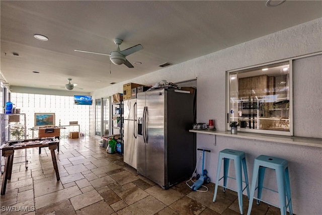 interior space featuring ceiling fan and stainless steel refrigerator with ice dispenser