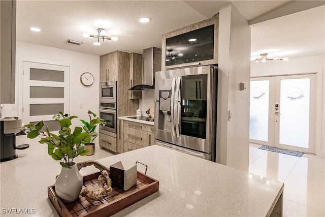 kitchen featuring a notable chandelier, french doors, appliances with stainless steel finishes, and wall chimney exhaust hood