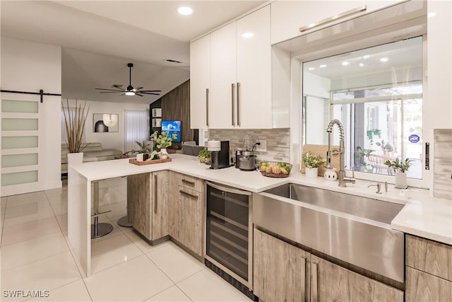 kitchen featuring beverage cooler, vaulted ceiling, a barn door, light tile patterned floors, and white cabinetry