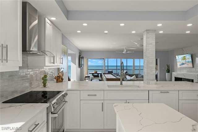 kitchen with white cabinetry, sink, wall chimney exhaust hood, and electric stove