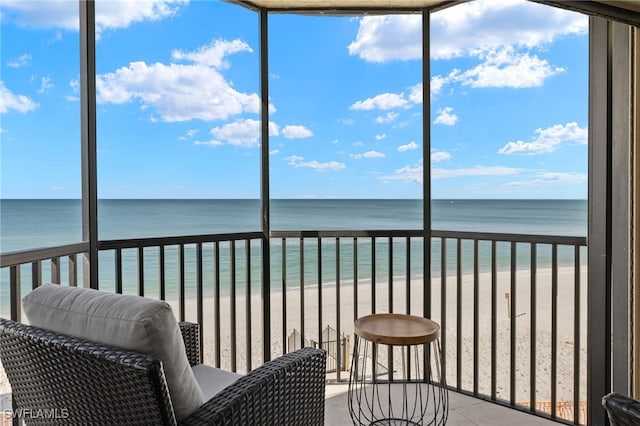 unfurnished sunroom with a wealth of natural light, a beach view, and a water view