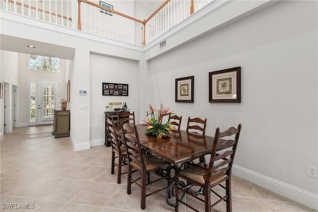 dining area with light tile patterned flooring and a towering ceiling