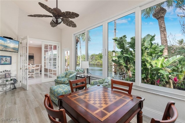 sunroom / solarium with french doors, ceiling fan, and a water view