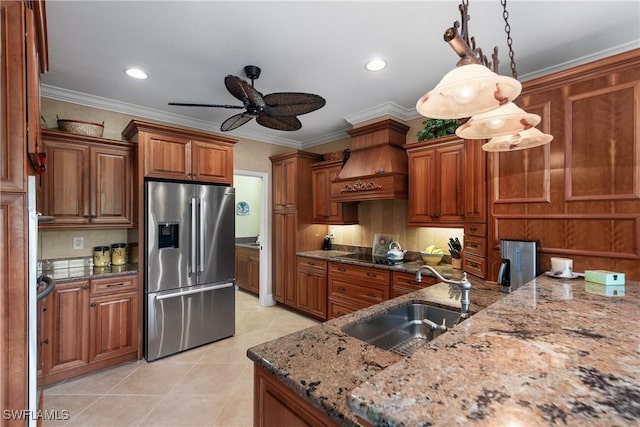 kitchen featuring sink, hanging light fixtures, dark stone countertops, ornamental molding, and stainless steel fridge